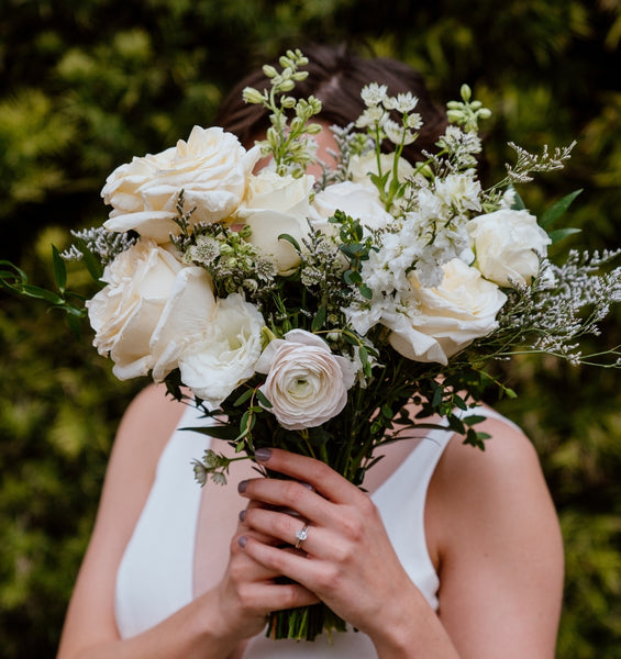 Primary of snow bridal bouquet with white and green flowers over bride's face